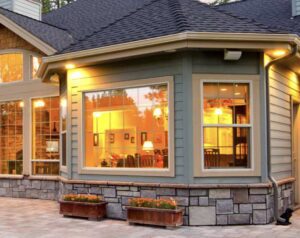 House exterior featuring a full seamless gutter run with a downspout, framed by elegant stone and siding.